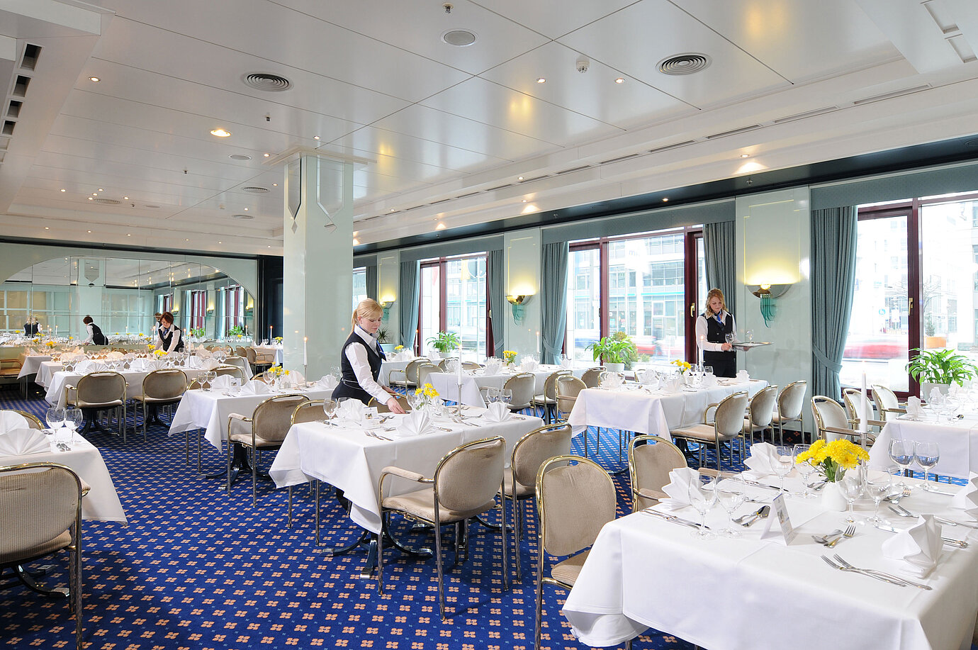 Sala de reuniones Salon Bonn en el Maritim Hotel Magdeburg con mesas vestidas de blanco, decoración elegante y personal atento.
