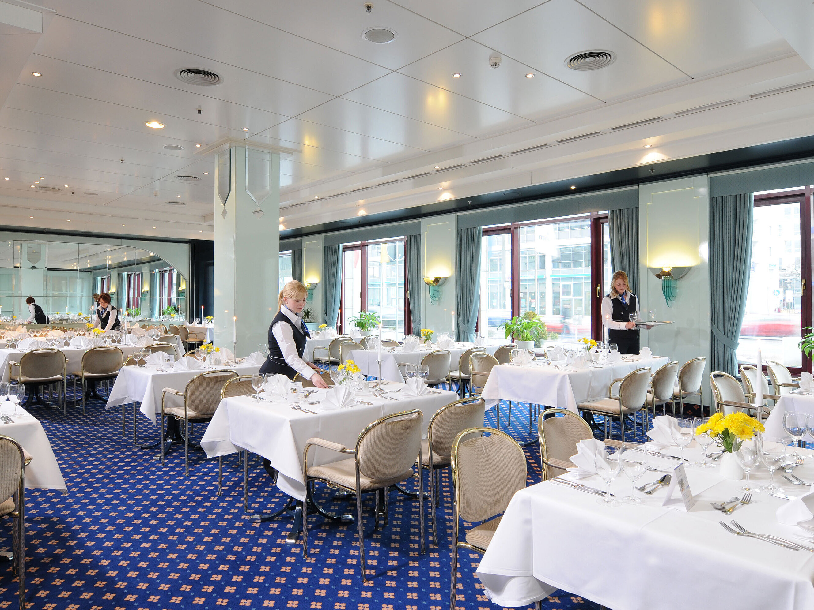 Sala de reuniones Salon Bonn en el Maritim Hotel Magdeburg con mesas vestidas de blanco, decoración elegante y personal atento.
