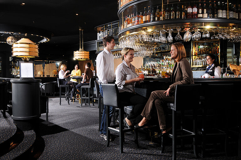 Ospiti che si godono drink e conversazioni al bar elegante del Maritim Hotel Monaco