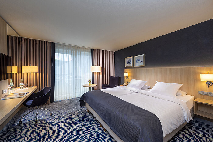 Espaciosa habitación Comfort en el Maritim Hotel Würzburg con escritorio, cama doble y ventanales de piso a techo