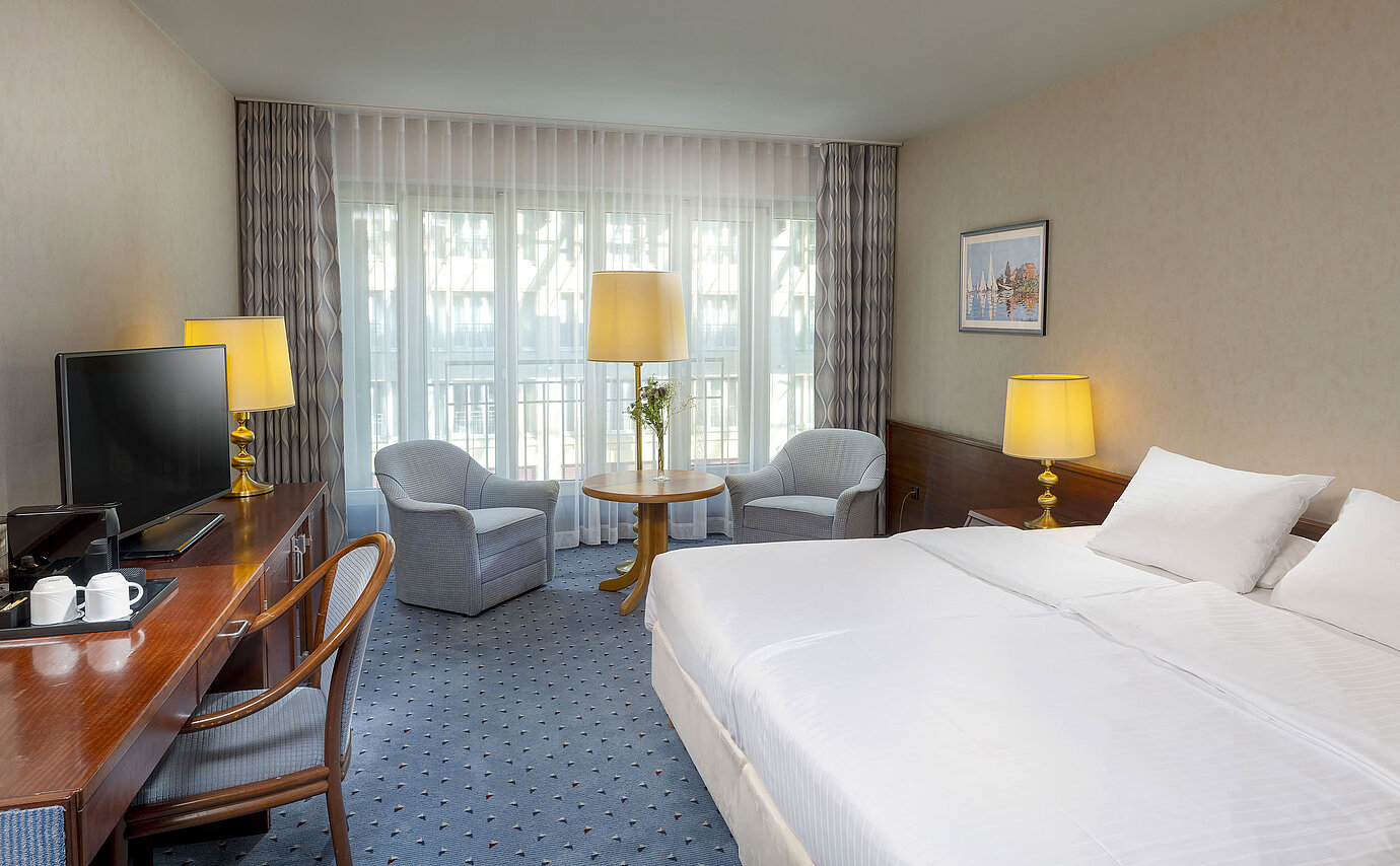 Camera Classic presso l'Hotel Maritim Colonia con letto matrimoniale, area salotto accogliente, scrivania e TV.
