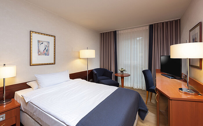 Camera singola classica al Maritim Hotel Würzburg con poltrona accogliente e arredo luminoso