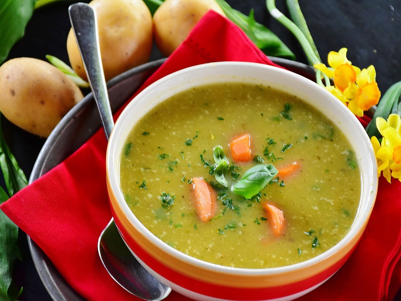 Creamy vegetable soup with fresh herbs Creamy vegetable soup with carrot pieces and fresh herbs served in a bowl.