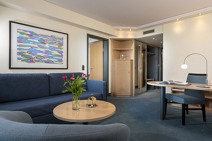 Suite moderne avec canapé, bureau et œuvre d'art stylée à l'hôtel Maritim proArte Berlin.