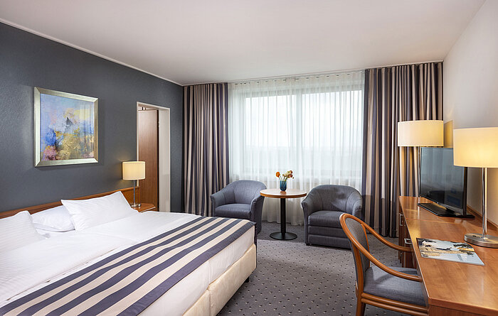 Camera di famiglia al Maritim Hotel Ulm con letto matrimoniale, scrivania, poltrone e luce naturale