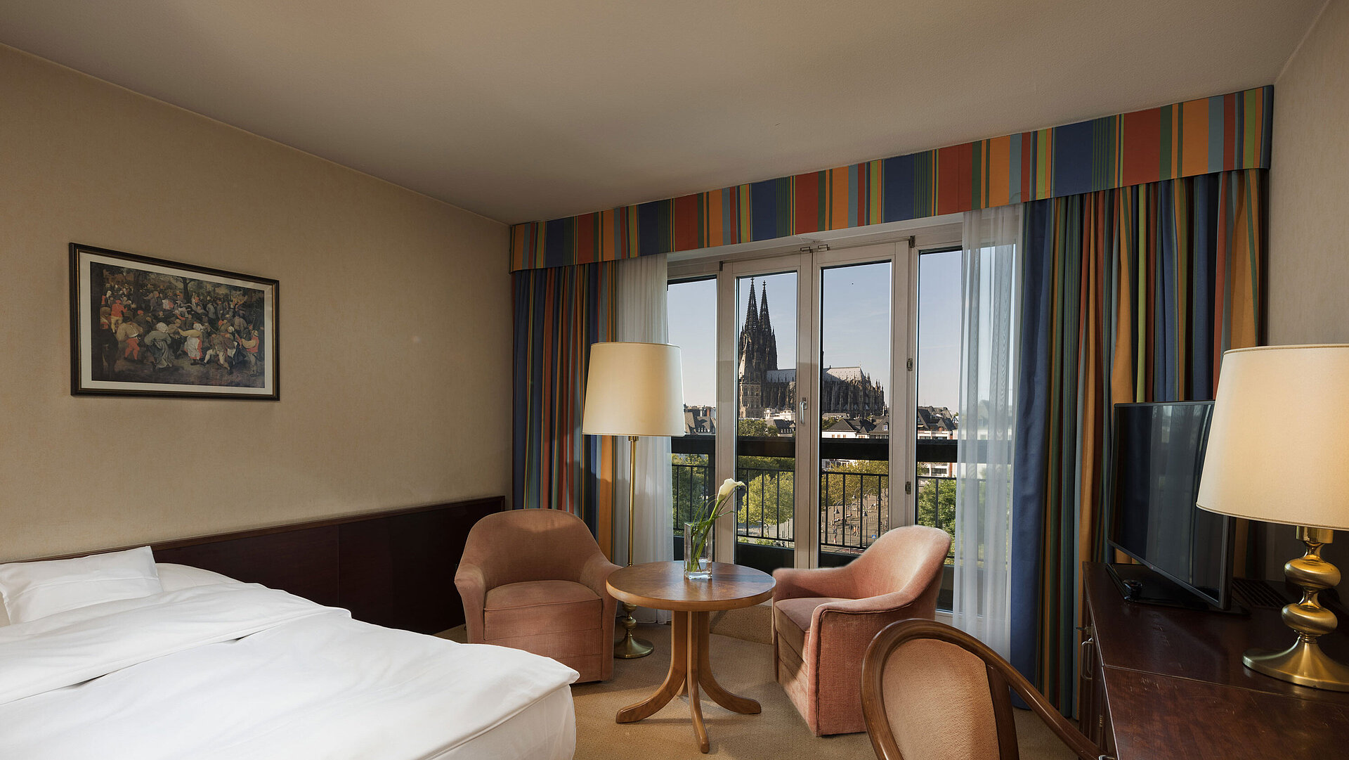 Chambre supérieure à l'hôtel Maritim Cologne avec coin salon, lit confortable et vue sur la cathédrale de Cologne.