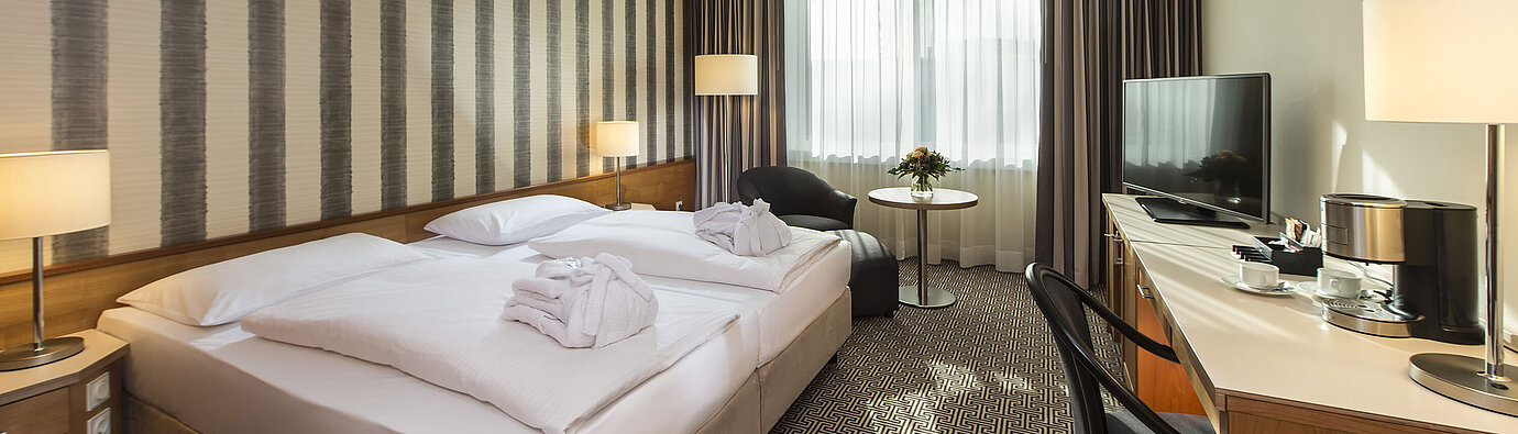 Chambre Superior  Chambre lumineuse avec bureau, fauteuils et grand lit à l’hôtel Maritim Stuttgart