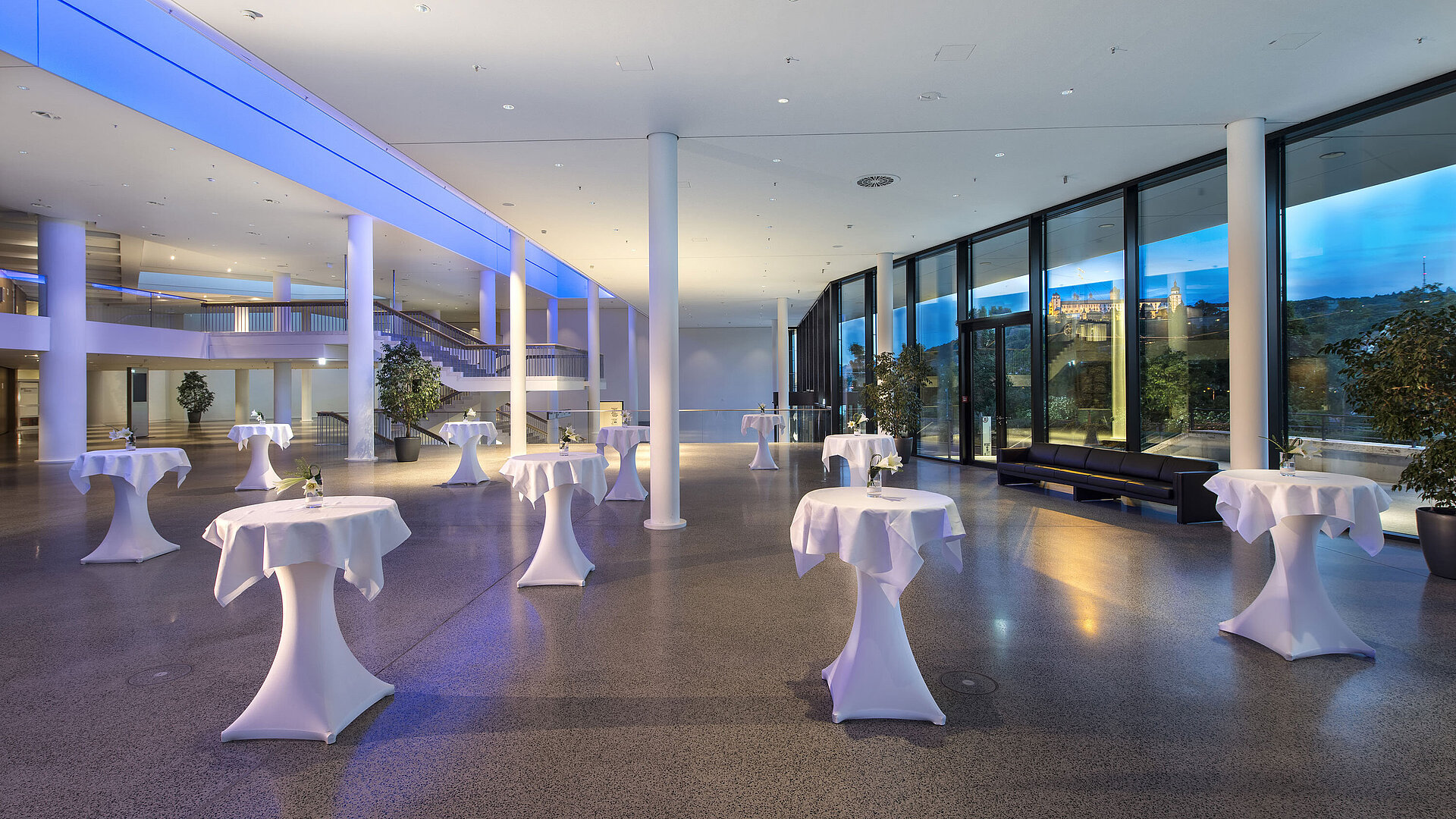 Foyer moderno del Maritim Hotel Würzburg con tavoli alti e vista sulla fortezza