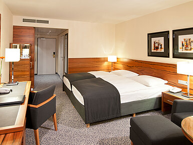 Double room with wood accents, seating area and desk at Maritim Hotel Munich