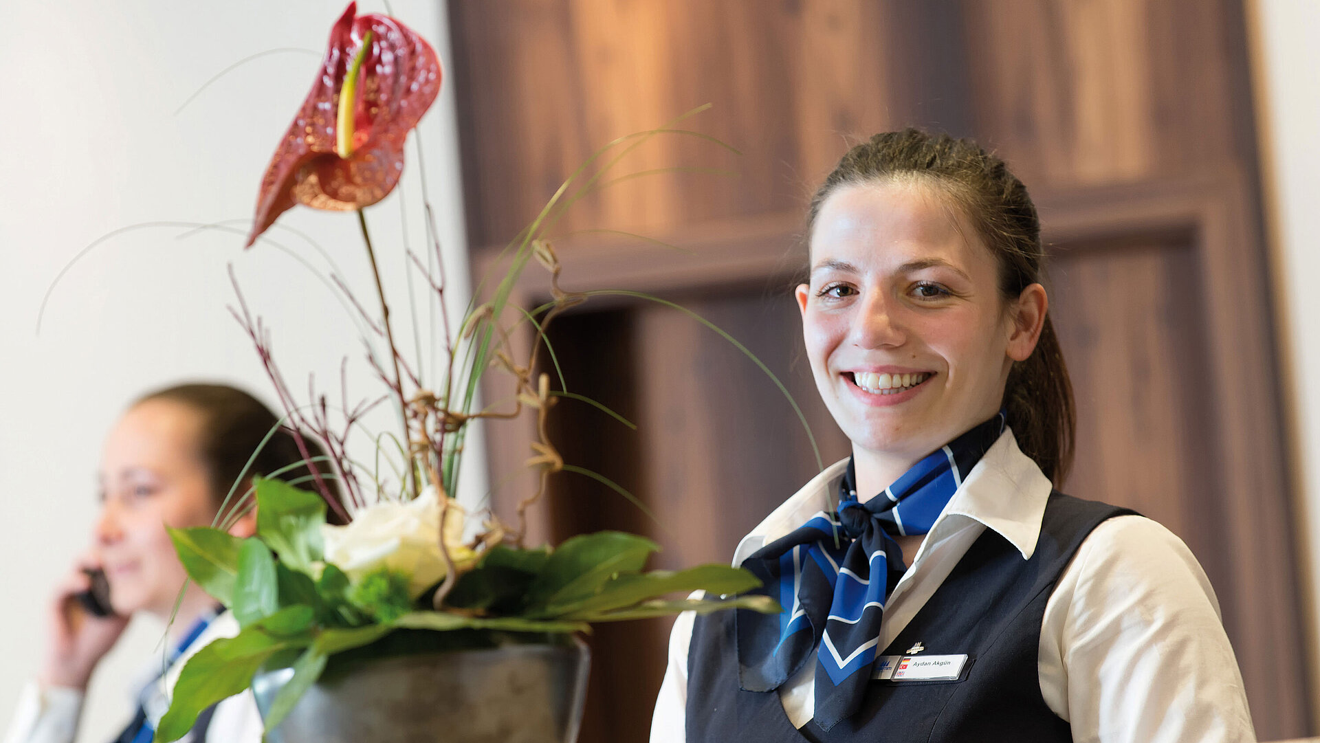 Friendly receptionist at Maritim Hotel Titisee with floral decoration in the foreground