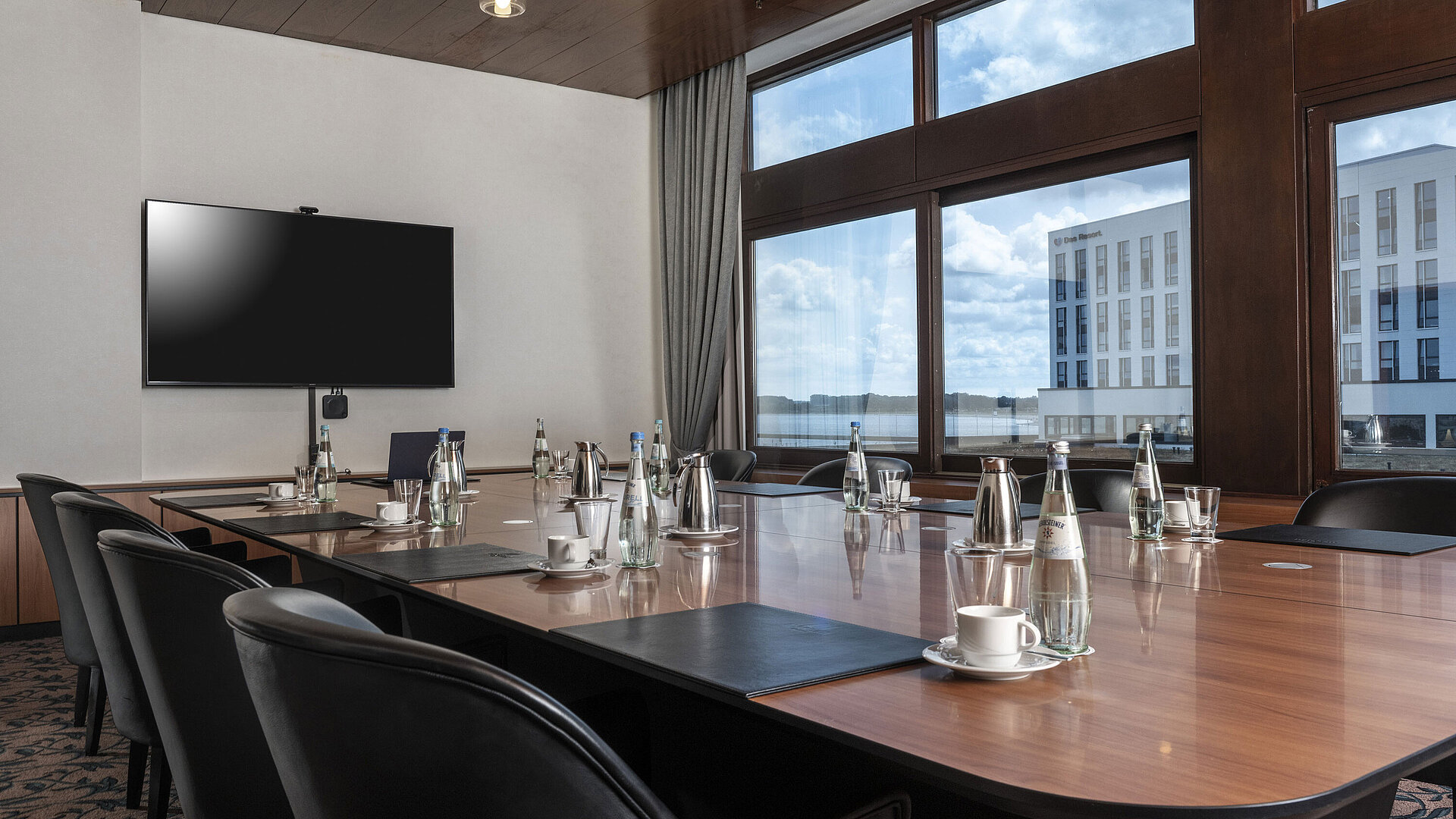 Salle de réunion moderne avec grande table, vue sur le lac et technologie à l'hôtel Maritim Travemünde