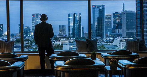 -Client admirant la vue panoramique sur la skyline de Francfort depuis la Sky Lounge du Maritim Hotel Frankfurt.