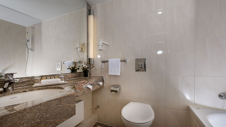 Bagno moderno al Maritim Seehotel Timmendorfer Strand con lavabo, specchio, doccia, WC e vasca.
