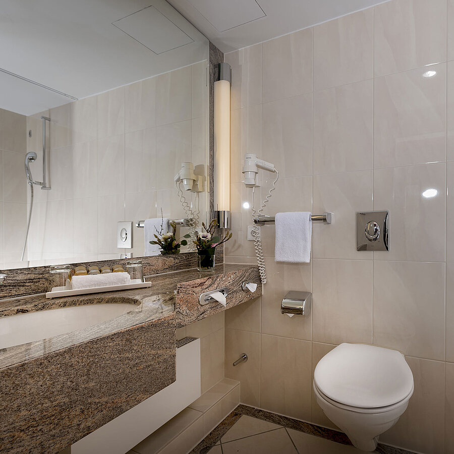 Modern bathroom at Maritim Seehotel Timmendorfer Strand with sink, mirror, shower, toilet, and bathtub.