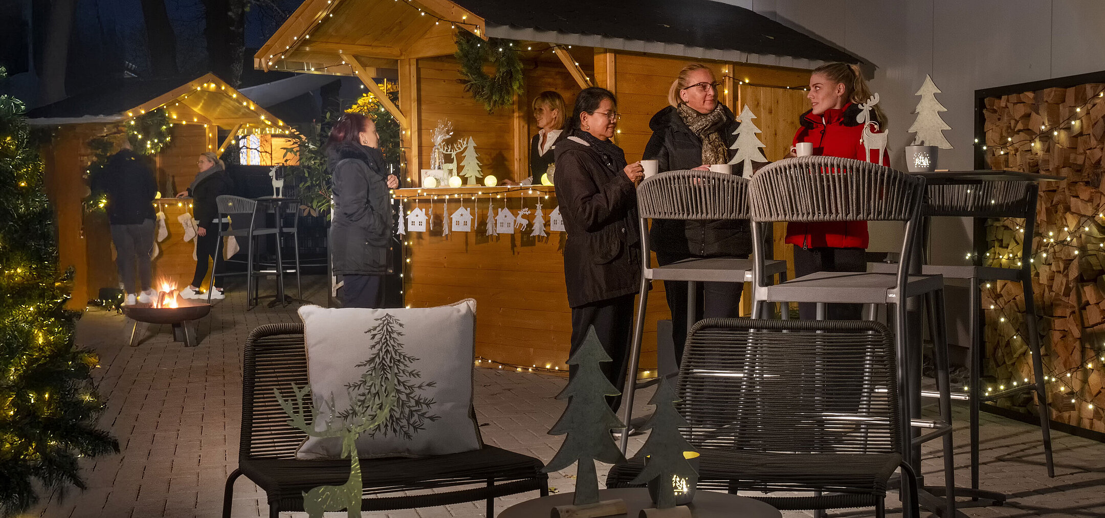 Maritim Christmas Village Lively Christmas market at Maritim Hotel Darmstadt with guests, festively decorated huts, and atmospheric lighting.