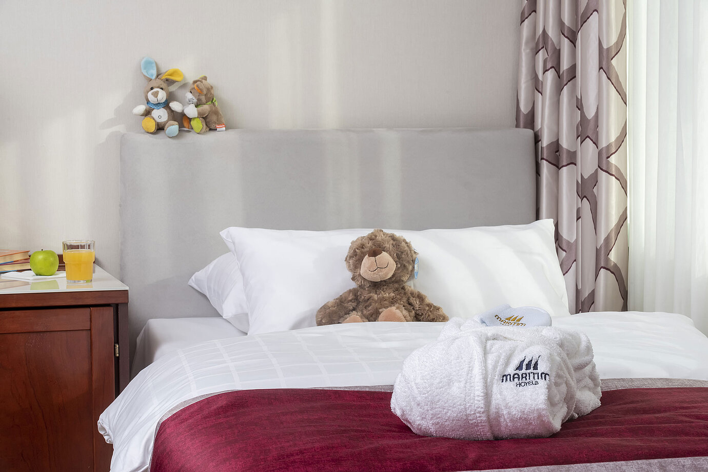 Suite familiare al Maritim Hotel Bonn con letto accogliente, peluche e accappatoio, perfetto per i bambini.