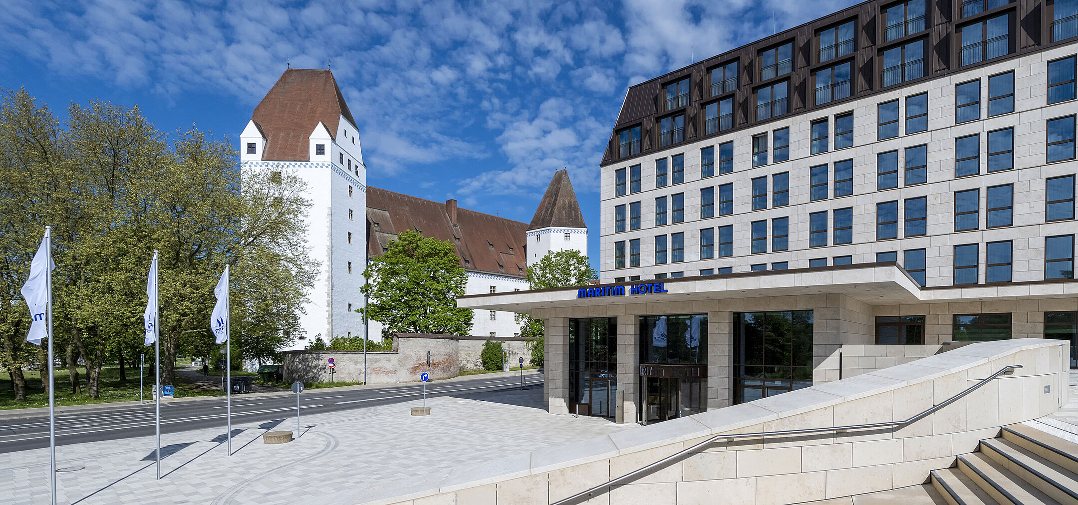 Modern Maritim Hotel Ingolstadt with the historic Neues Schloss in the background and a welcoming entrance.