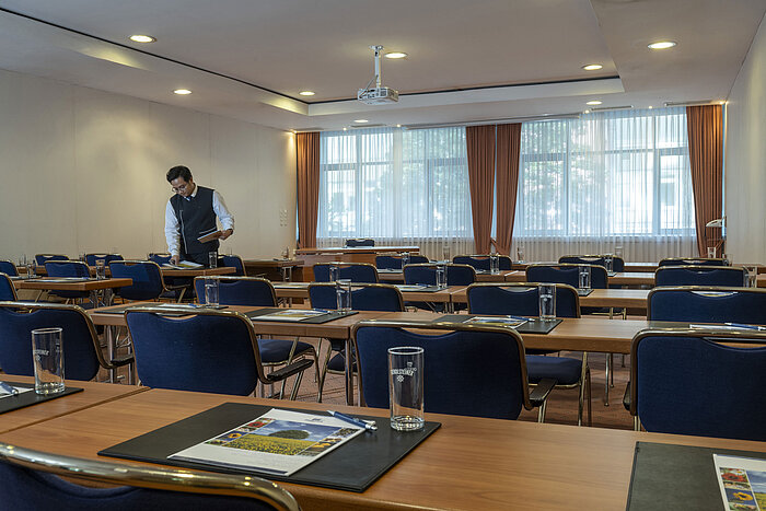 Sala de reuniones luminosa en el Maritim Hotel Magdeburg con asientos en fila, luz natural y equipamiento moderno.