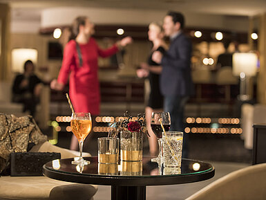 Table with cocktails and drinks while guests dance at the bar of Maritim Seehotel Timmendorfer Strand.