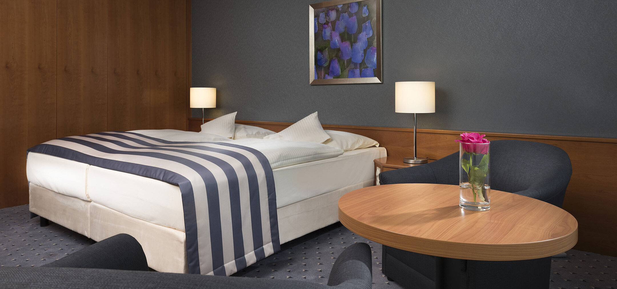 Habitación doble acogedora en el Maritim Hotel Ulm con rincón de descanso y rosa fresca