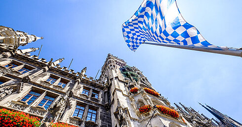 © fottoo - AdobeStock.com Bandera bávara sobre Marienplatz con el ayuntamiento histórico de Múnich