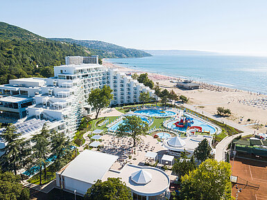 Aerial view of the resort with pools, beach, modern hotel building and coastline