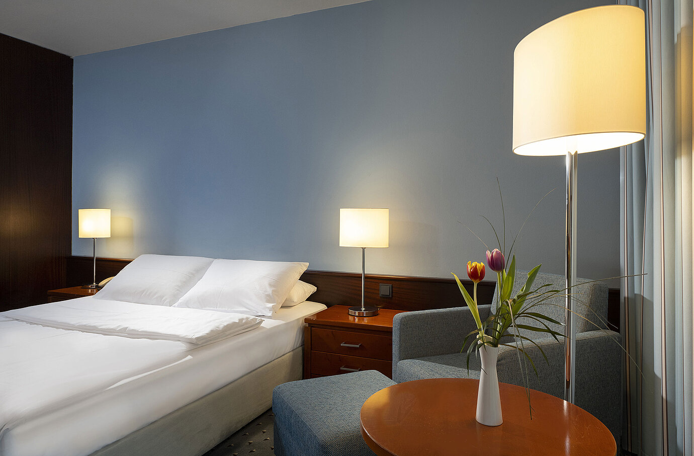 Comfortable single room with queen-size bed, modern furniture, and ambient lighting at the Maritim Hotel Darmstadt.