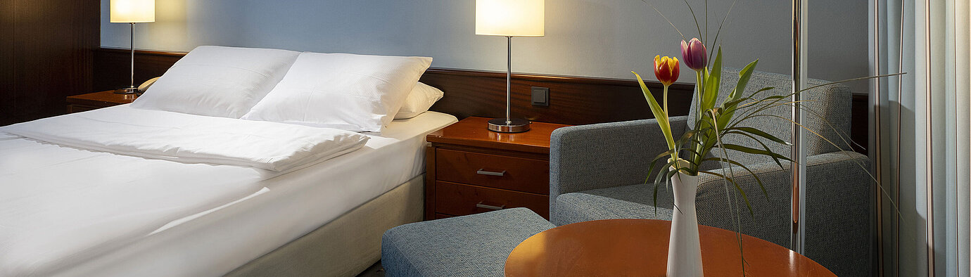 Camera singola confortevole con letto queen-size, mobili moderni e luce ambientale al Maritim Hotel Darmstadt.