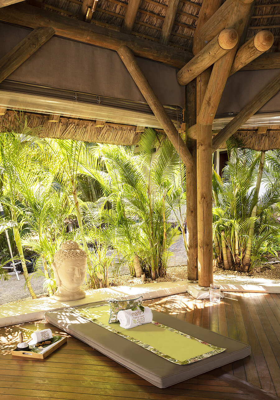 Lit de spa extérieur entouré de verdure avec statue de Bouddha et ambiance tropicale