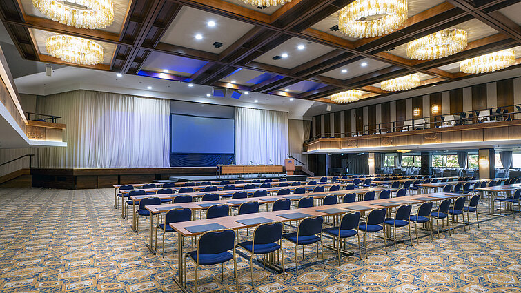 Sala spaziosa con palco, schermo e sedute in fila al Maritim Hotel Travemünde