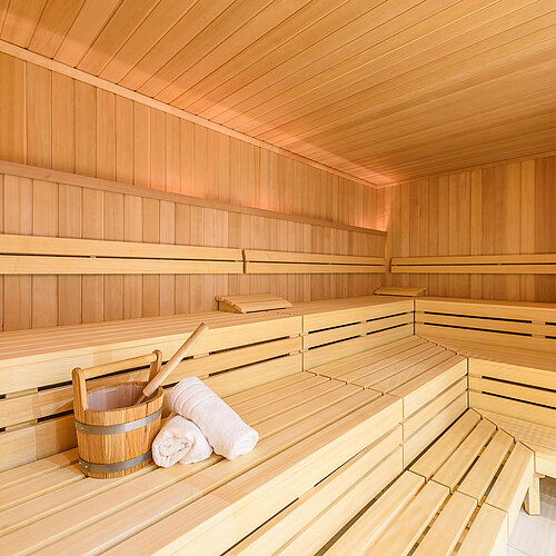 Sauna confortable avec bancs en bois, seau de sauna et serviette, parfait pour se détendre au Maritim Hotel Bremen.