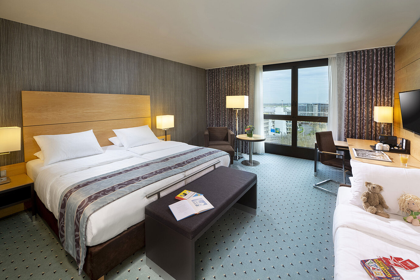 Chambre familiale supérieure spacieuse au Maritim Hotel Düsseldorf avec grand lit, lit supplémentaire et vue sur la ville.