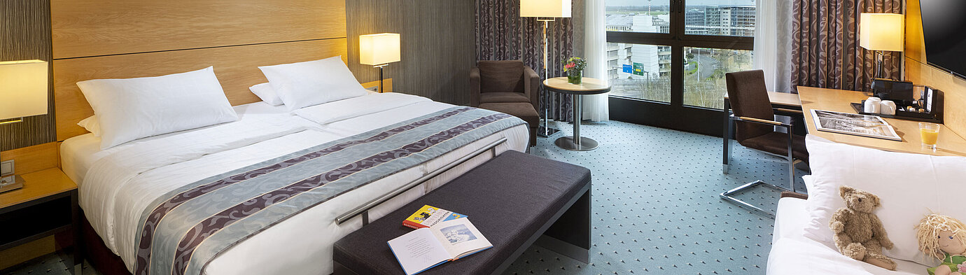 Chambre familiale supérieure spacieuse au Maritim Hotel Düsseldorf avec grand lit, lit supplémentaire et vue sur la ville.