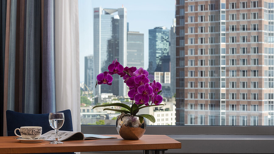 Vue depuis la chambre du Maritim Hotel Frankfurt avec panorama sur la skyline, bureau et orchidée élégante.