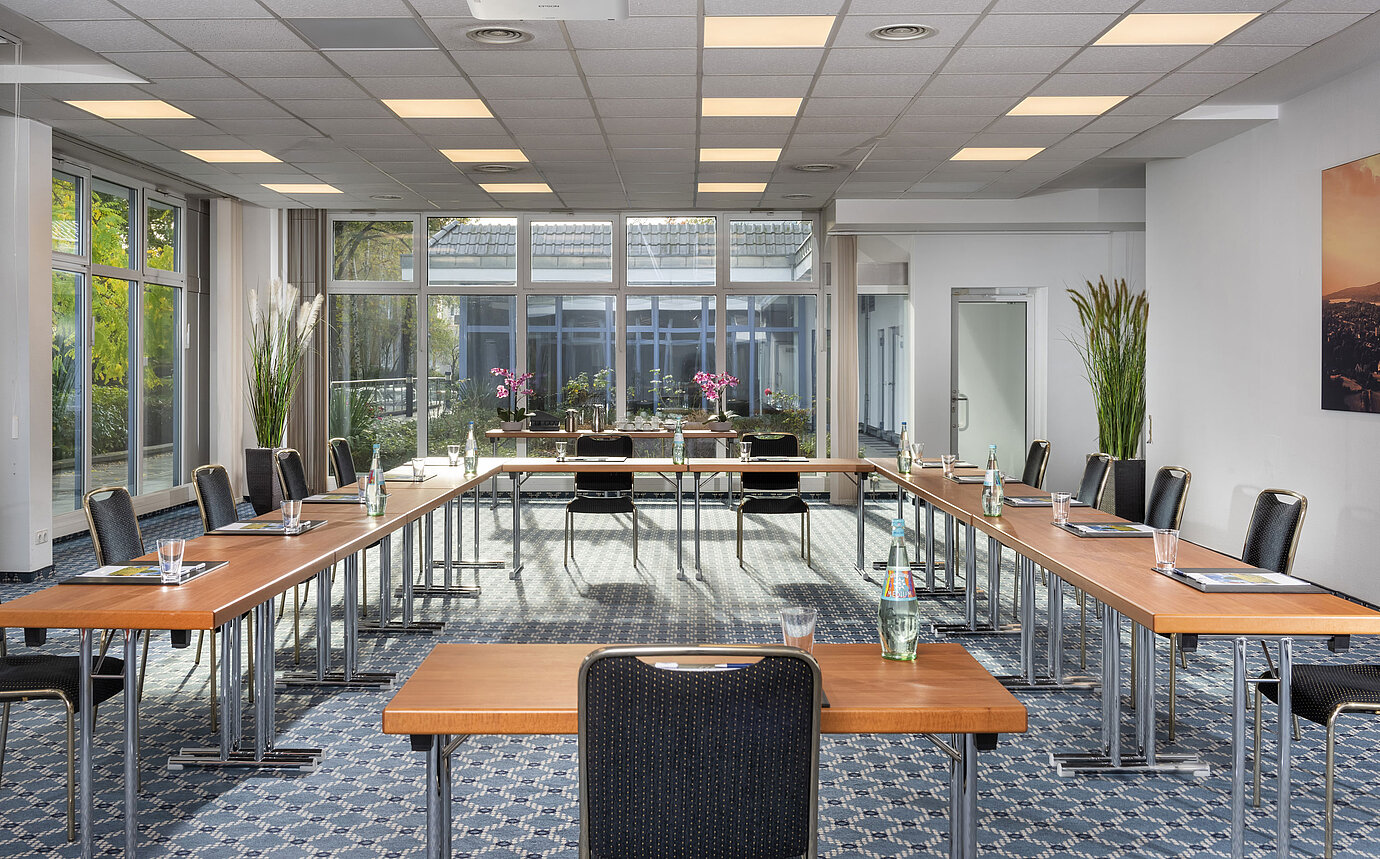 Sala de conferencias luminosa con grandes ventanales y vista al patio en el Maritim Hotel Königswinter.