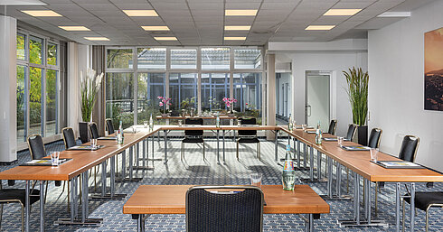 Sala de conferencias luminosa con grandes ventanales y vista al patio en el Maritim Hotel Königswinter.