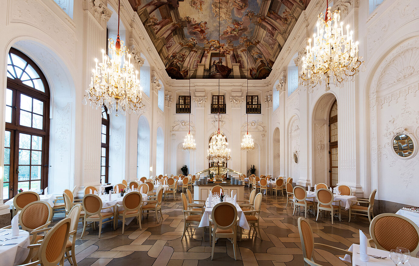Elegante Salón Apollo en Maritim Hotel Fulda con lámparas, techo con frescos y mesas sofisticadas.