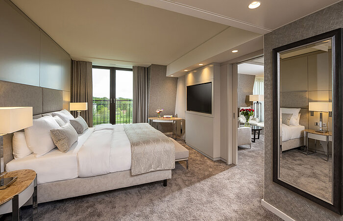 Dormitorio elegante con cama grande, interior sofisticado y ventanales con vistas en el Maritim Hotel Ingolstadt.