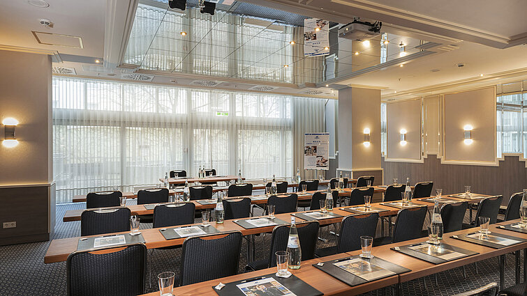 Salle de réunion avec fenêtres, tables et bouteilles d’eau à l’hôtel Maritim Munich