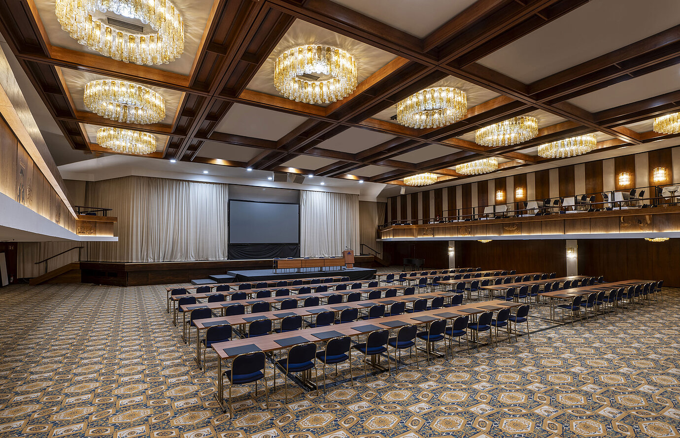 Sala espaciosa con escenario, pantalla y asientos en fila en el Maritim Hotel Travemünde