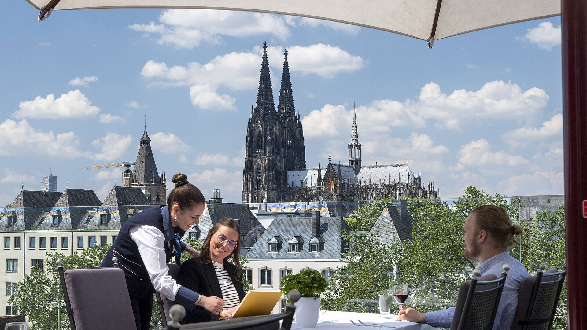 Los huéspedes disfrutan del servicio en la terraza del Hotel Maritim Colonia con vistas a la catedral de Colonia.