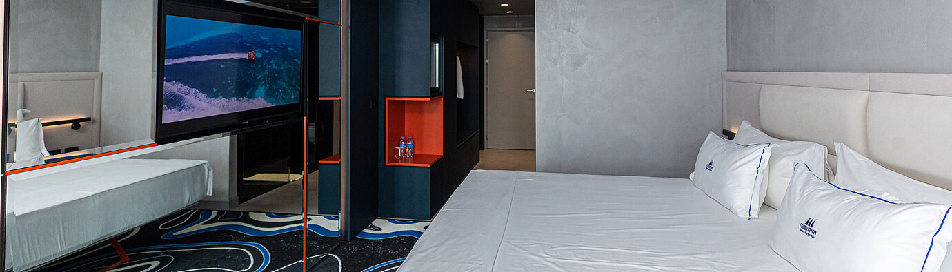 Habitación amplia en el Maritim Resort Marina Bay con gran espejo, TV y cama doble