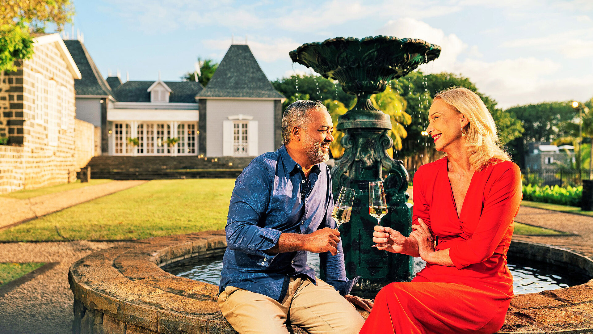 Couple savourant un verre de vin près d’une fontaine dans un jardin