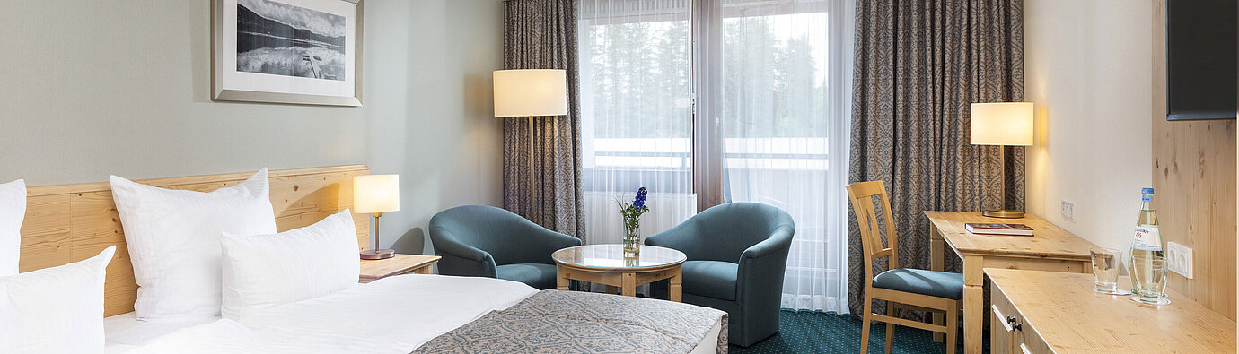 Bright double room at Maritim TitiseeHotel with seating area, desk and forest view