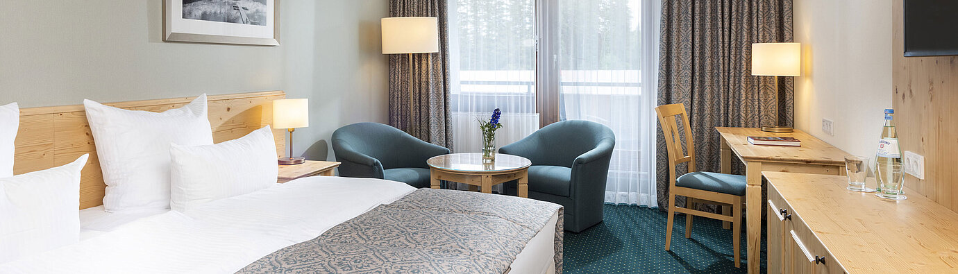 Comfort room Bright double room at Maritim TitiseeHotel with seating area, desk and forest view