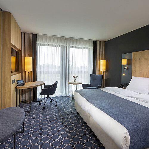 Spacious double room at Maritim Hotel Ingolstadt with desk, seating area, and balcony.