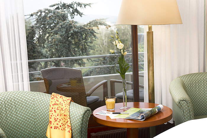 Coin salon confortable au Maritim Hotel Bad Salzuflen avec vue sur le balcon et verdure