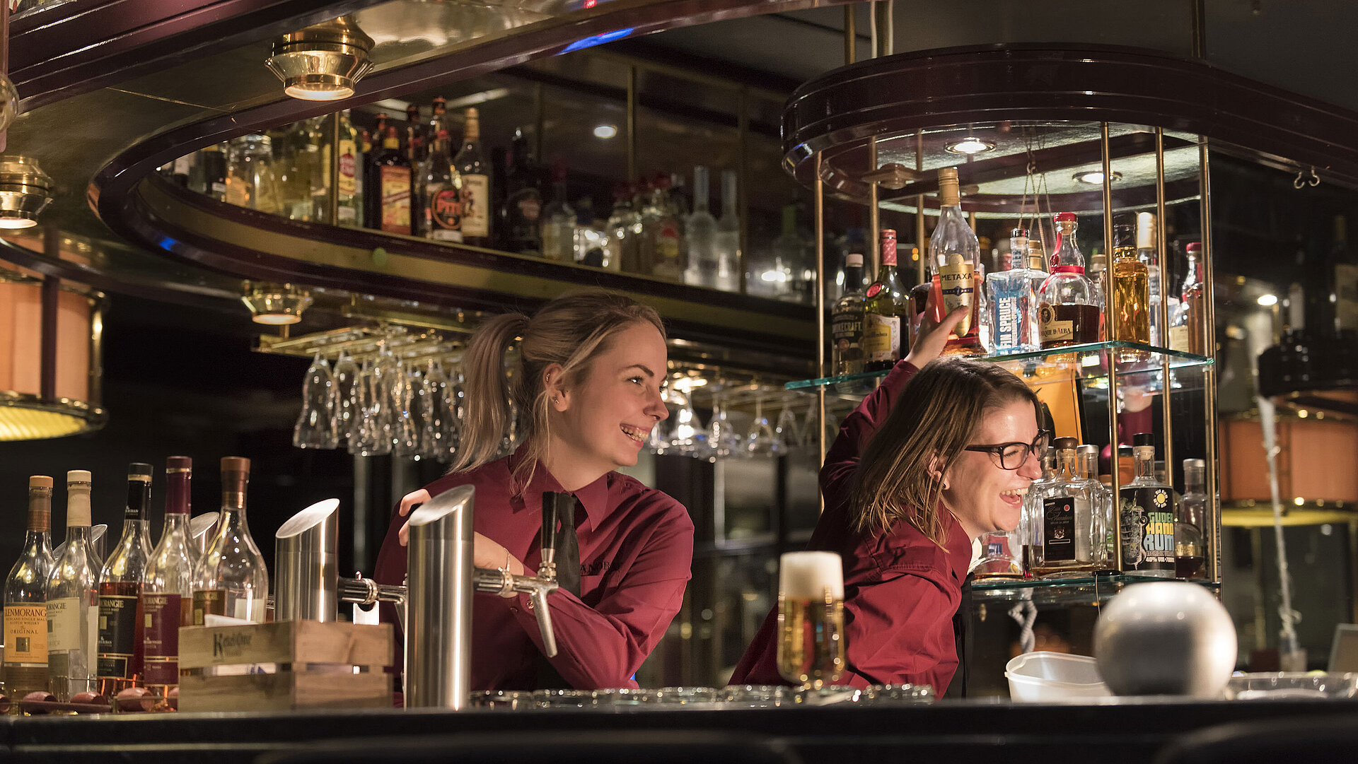 Baristi al piano bar del Maritim Hotel Bonn, circondati da una vasta selezione di alcolici e bevande.