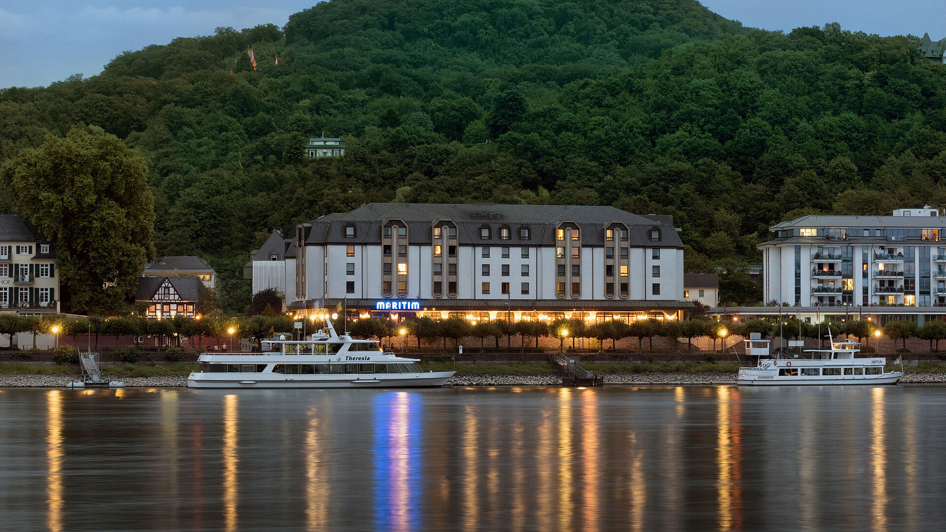 Maritim Hotel Königswinter at night with atmospheric lighting and a view of the Rhine.
