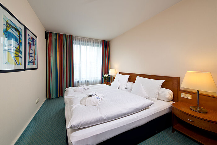 Camera della suite master al Maritim Hotel Frankfurt con letto matrimoniale, arredi moderni e atmosfera rilassante.